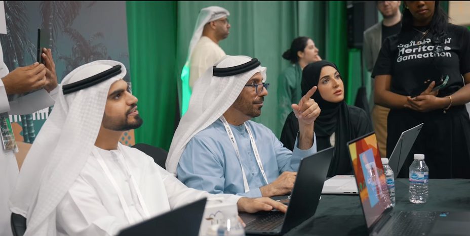 Judges seated along a table of laptops, one pointing at a screen off-camera.